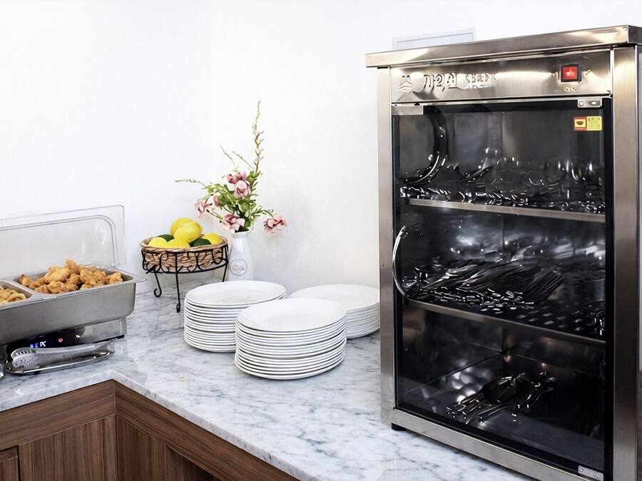 A buffet setup with food containers, plates, and a beverage dispenser.