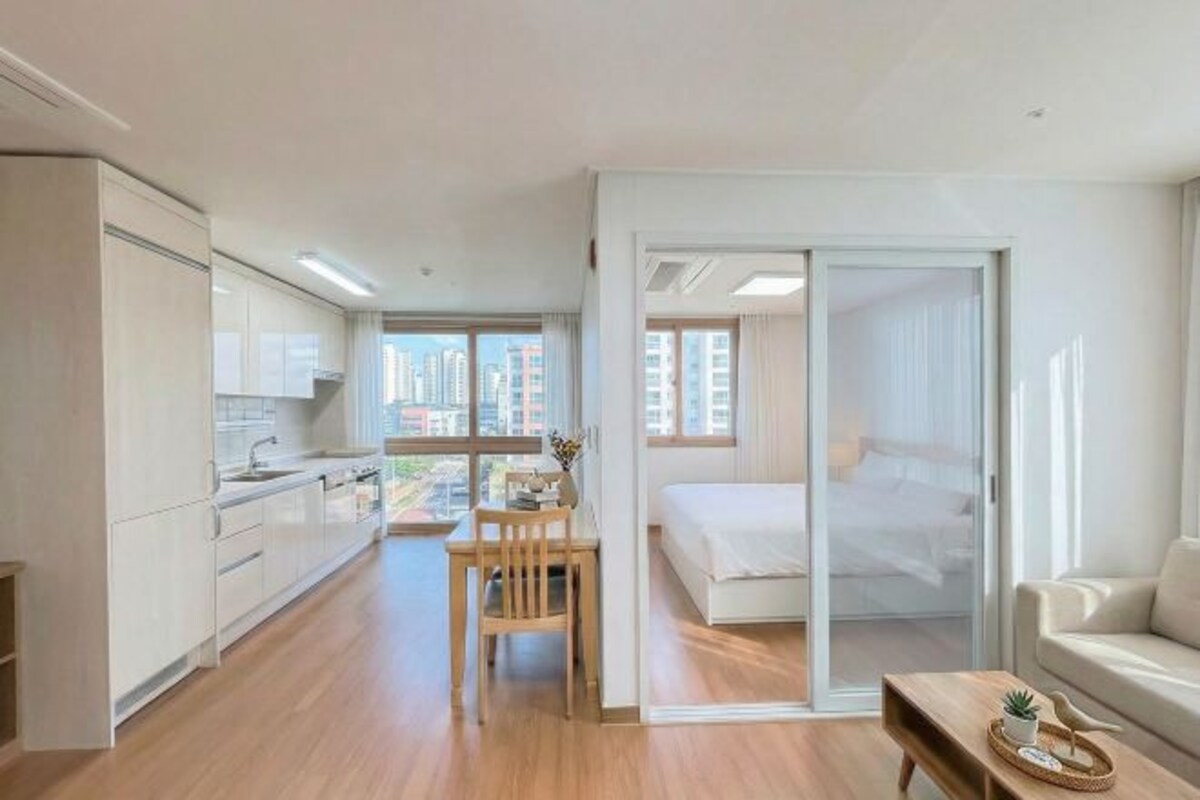 Un apartamento moderno con cocina, comedor y un dormitorio con puerta corrediza al balcón.