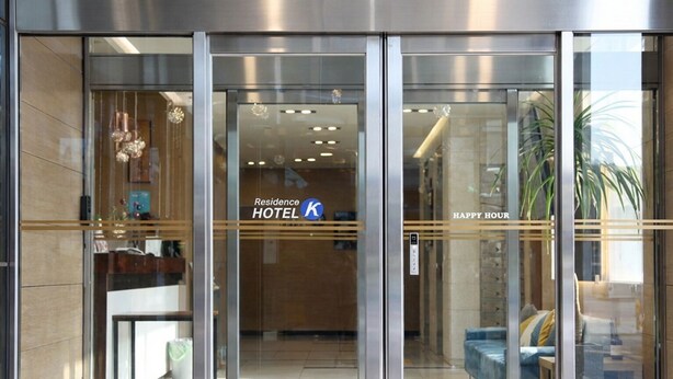 Entrada de un hotel con una recepción, un área de estar con sofá y un letrero que dice "Residence HOTEL HAPPY HOUR".