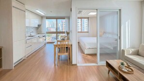 Un apartamento moderno con cocina, comedor y un dormitorio con puerta corrediza de vidrio a un balcón.