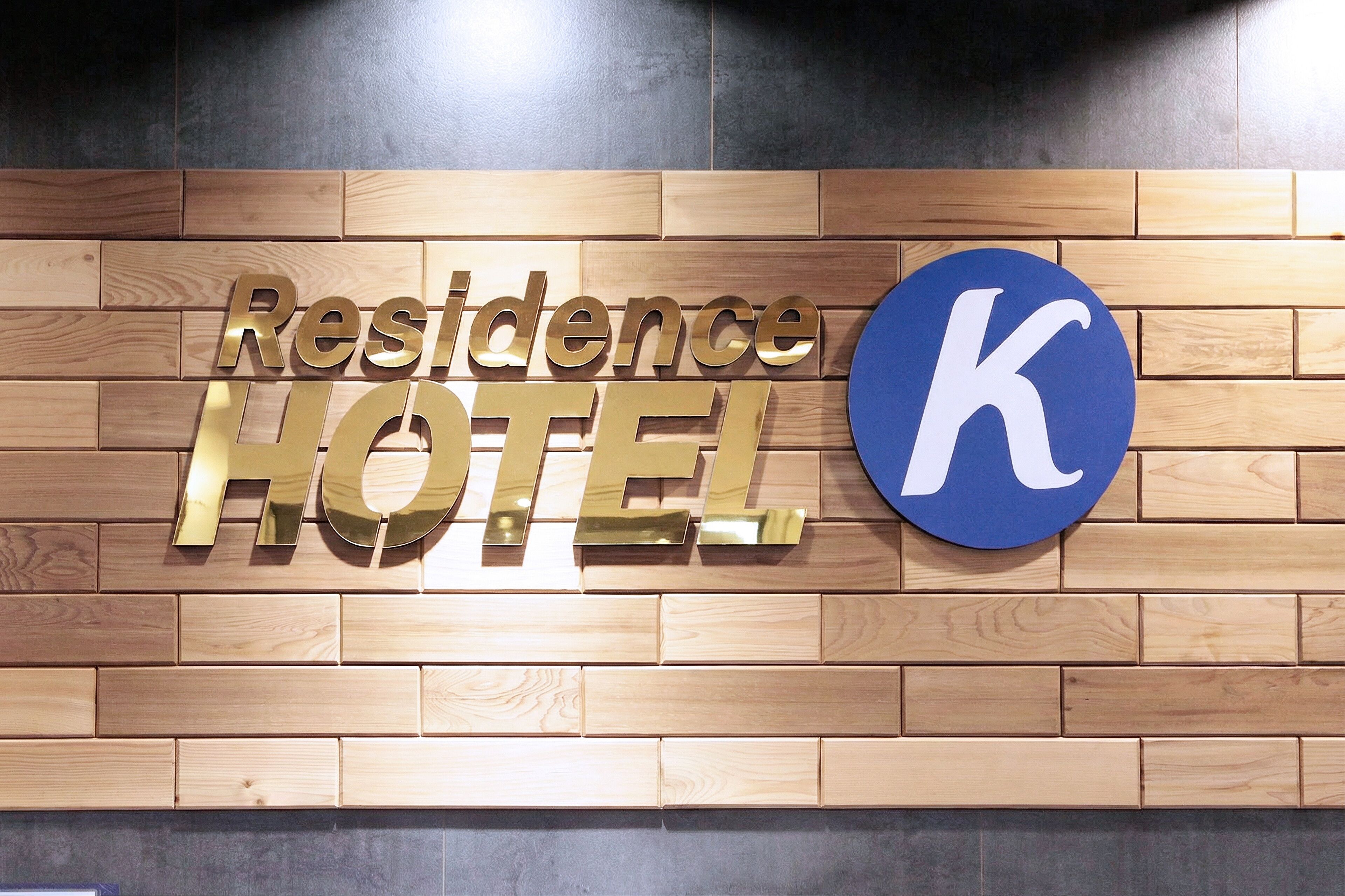 A wooden wall with the words "Residence Hotel" and a large blue 'K' logo.