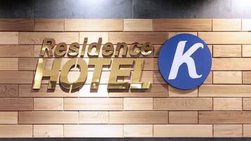 A wooden wall with the words "Residence Hotel" and a large blue 'K' logo.