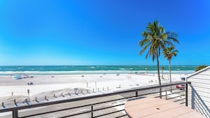 Un balcón con vista a una playa, palmeras y el océano.