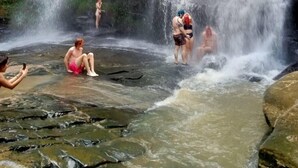 A waterfall in a natural setting with people enjoying the water. - The Elephant B&B (Chiangmai)