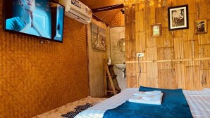 A cozy room with a bed, a TV, and a wooden wall. - The Elephant B&B (Chiangmai)