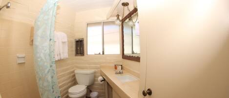 A compact bathroom with a toilet, sink, and shower area.