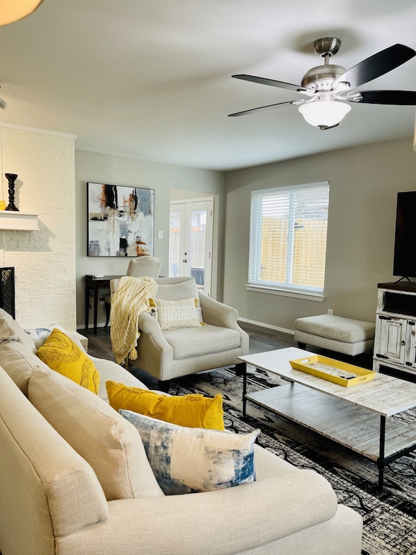 Un salon comprenant un canapé, un fauteuil, une table basse et un ventilateur de plafond.