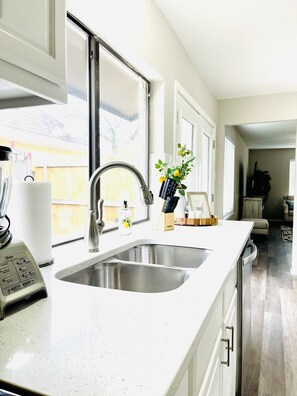 A modern kitchen with a stainless steel sink, a built-in oven, and a window providing natural light. - Modern and Stylish updated home (Lake Dallas)