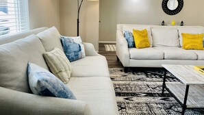 Un salon moderne avec un canapé, une table basse et un lampadaire.