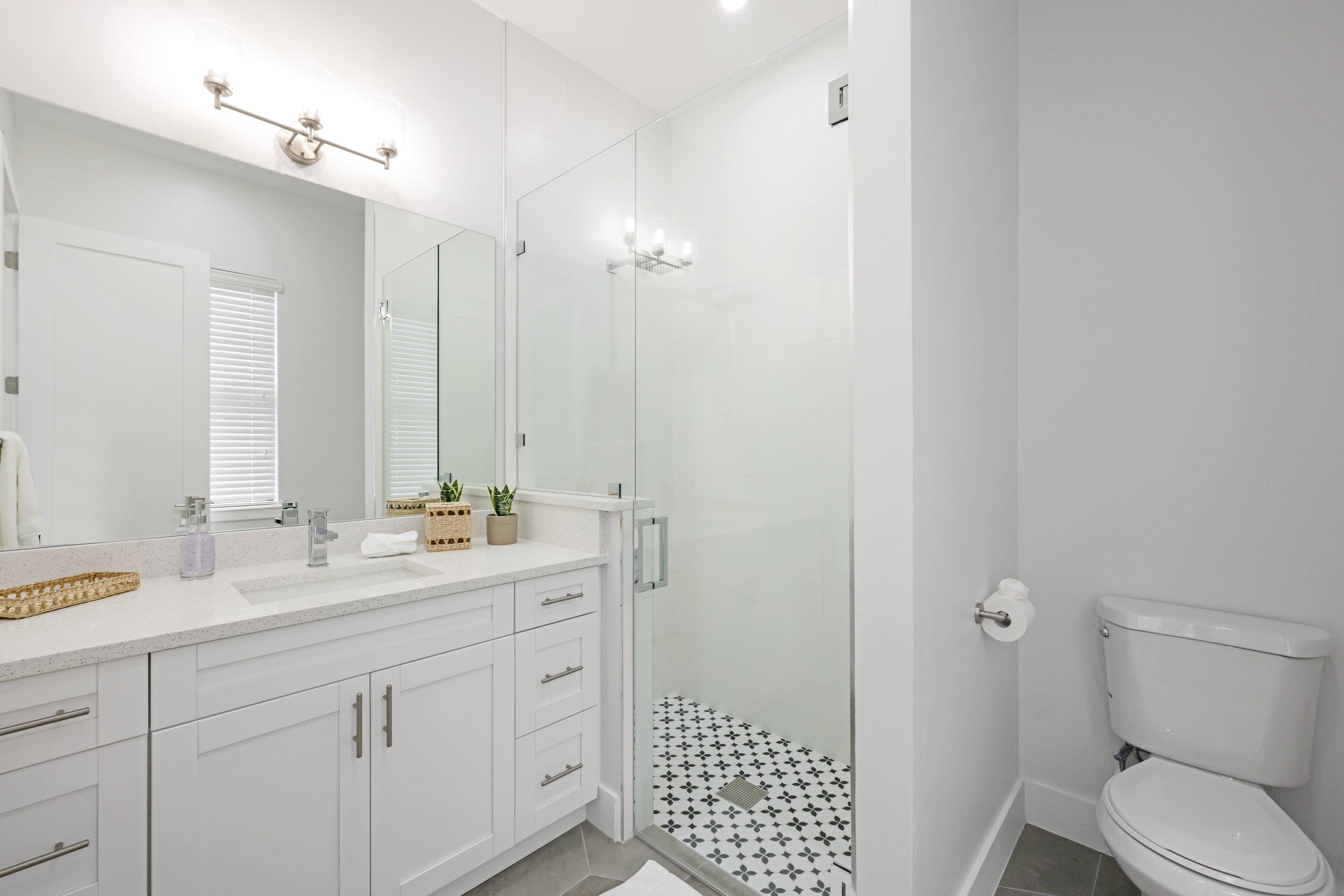 A modern bathroom with a glass shower enclosure, a white toilet, and a vanity with a mirror.