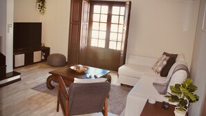 A living room with a sofa, a coffee table, a television, and a potted plant. - Quiet, Comfortable & Amazing Location (Óbidos)