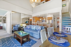 A spacious living area with a sofa, coffee table, and dining table set for a meal.
