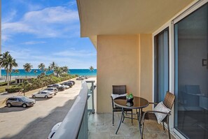 Enjoy ocean views and palm trees from this beachfront balcony, perfect for dining or relaxing.