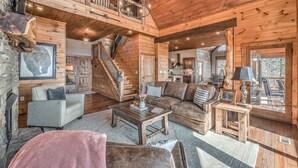 A log cabin interior with a living room, a staircase, and a dining area. - Branch Oak Manor - Million Dollar Views | Hot Tub | Fire Pit (Mineral Bluff)