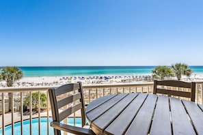 Een balkon met uitzicht op een strand en zwembad.