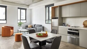 A modern kitchen with a dining area, large windows, and a built-in oven. - Punthill Parramatta (Parramatta)