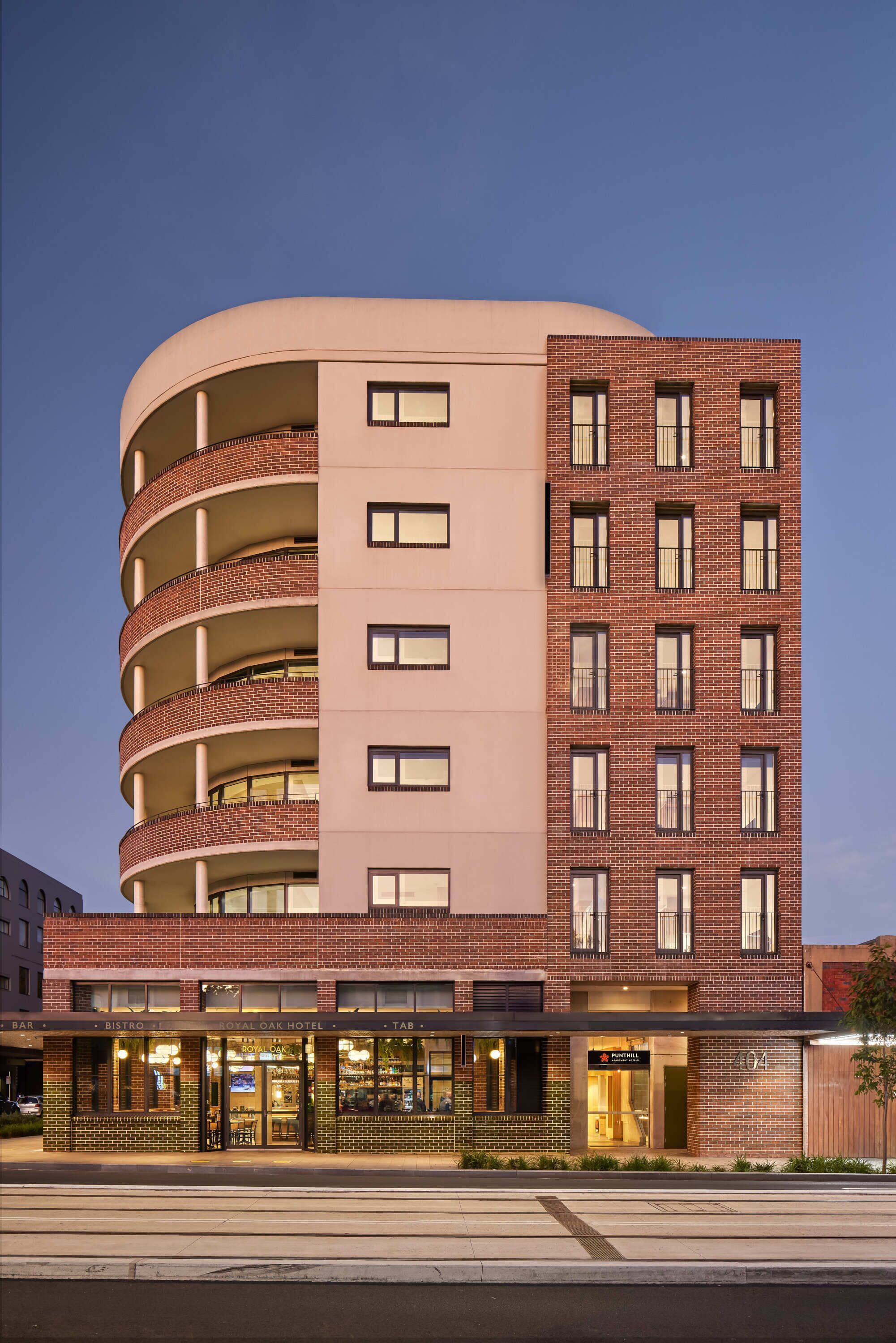 Et hotel med flere etager, en buet facade, altaner og butikker i stueetagen.