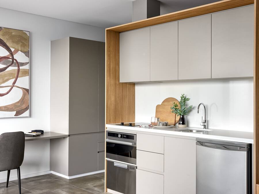 A modern kitchen with built-in appliances, a wooden countertop, and a dining area with a chair.