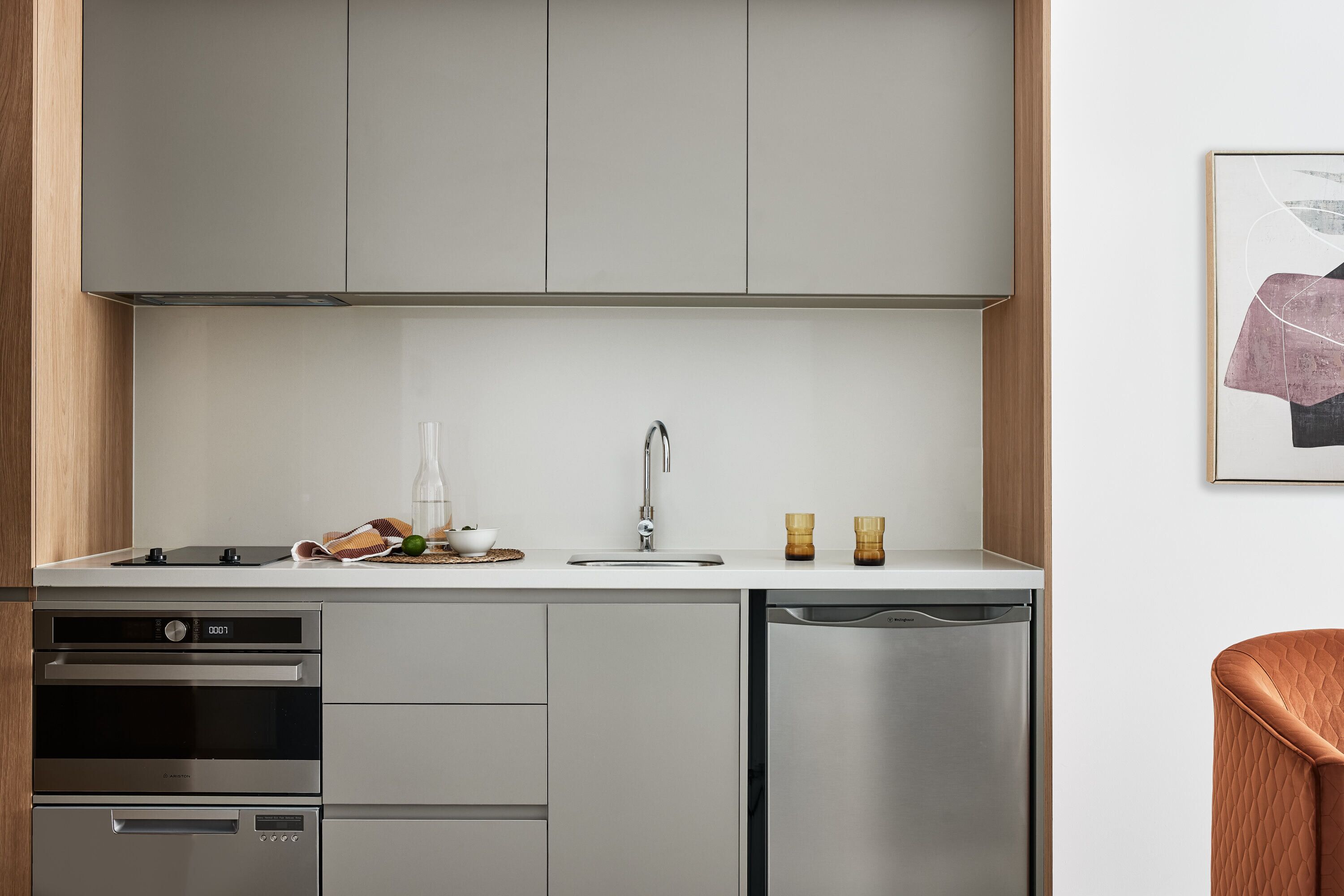 Una cocina moderna con electrodomésticos de acero inoxidable, lavavajillas y una encimera con fregadero y objetos decorativos.