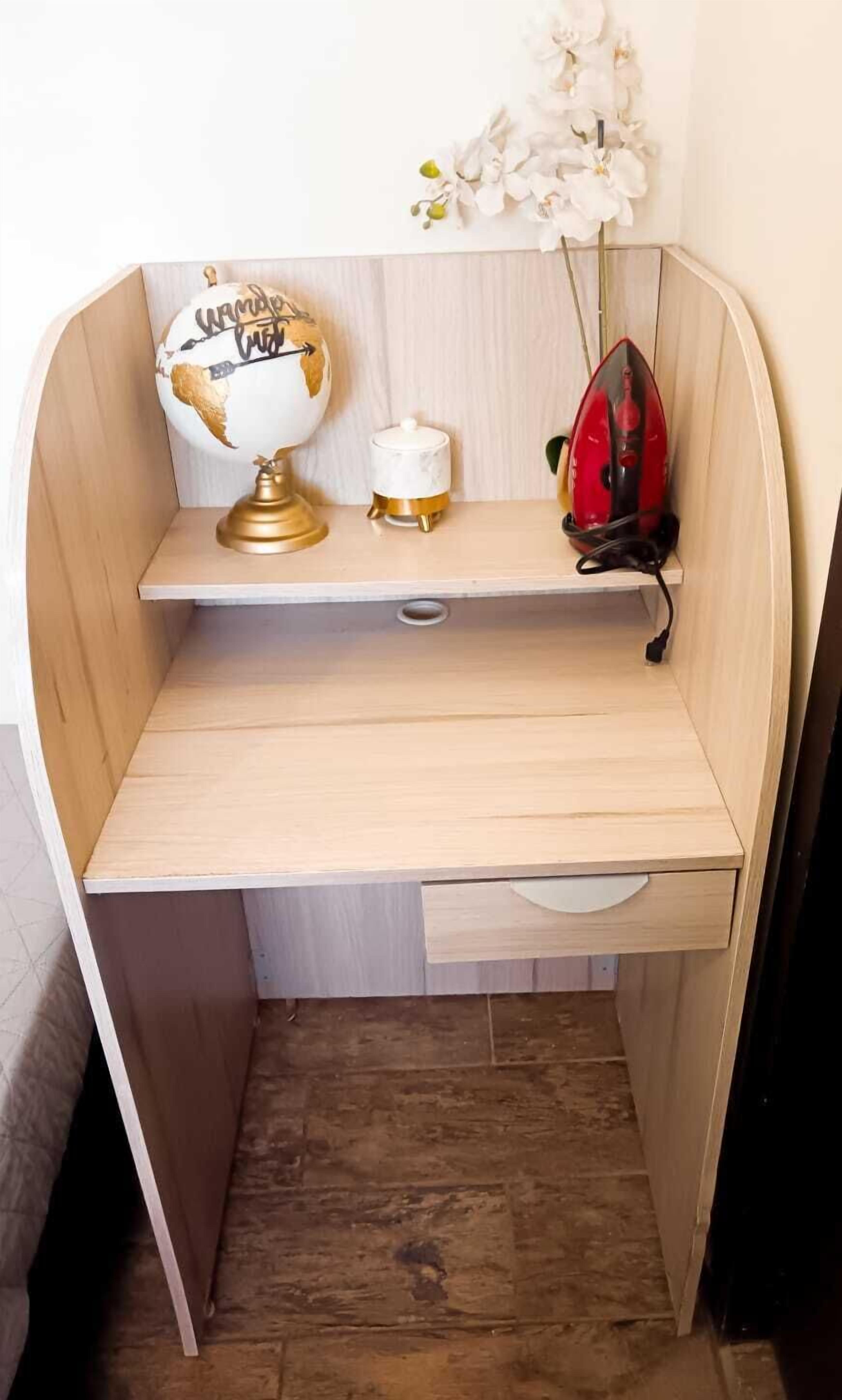 Un bureau compact en bois, sur lequel on peut voir un globe terrestre, un petit récipient blanc et un objet rouge, le tout posé sur une étagère.
