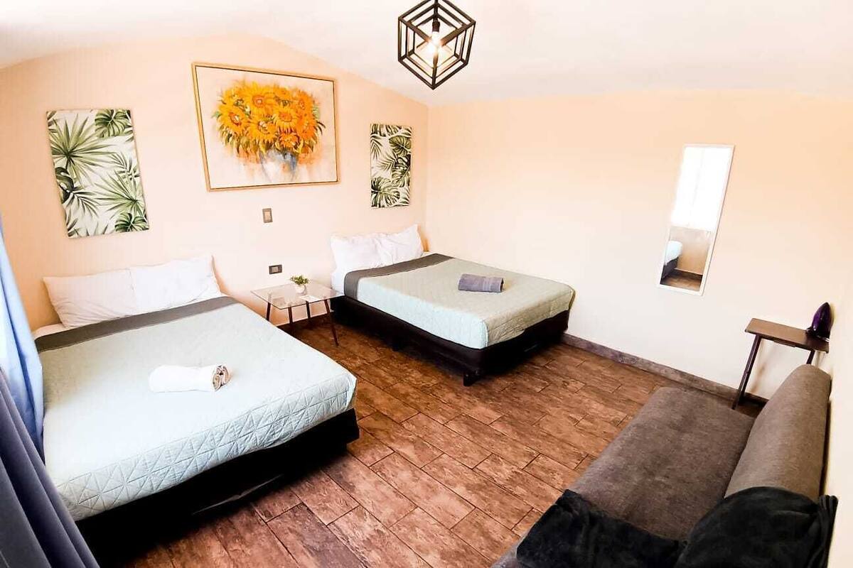 A hotel room with two beds, a sofa, and a mirror.