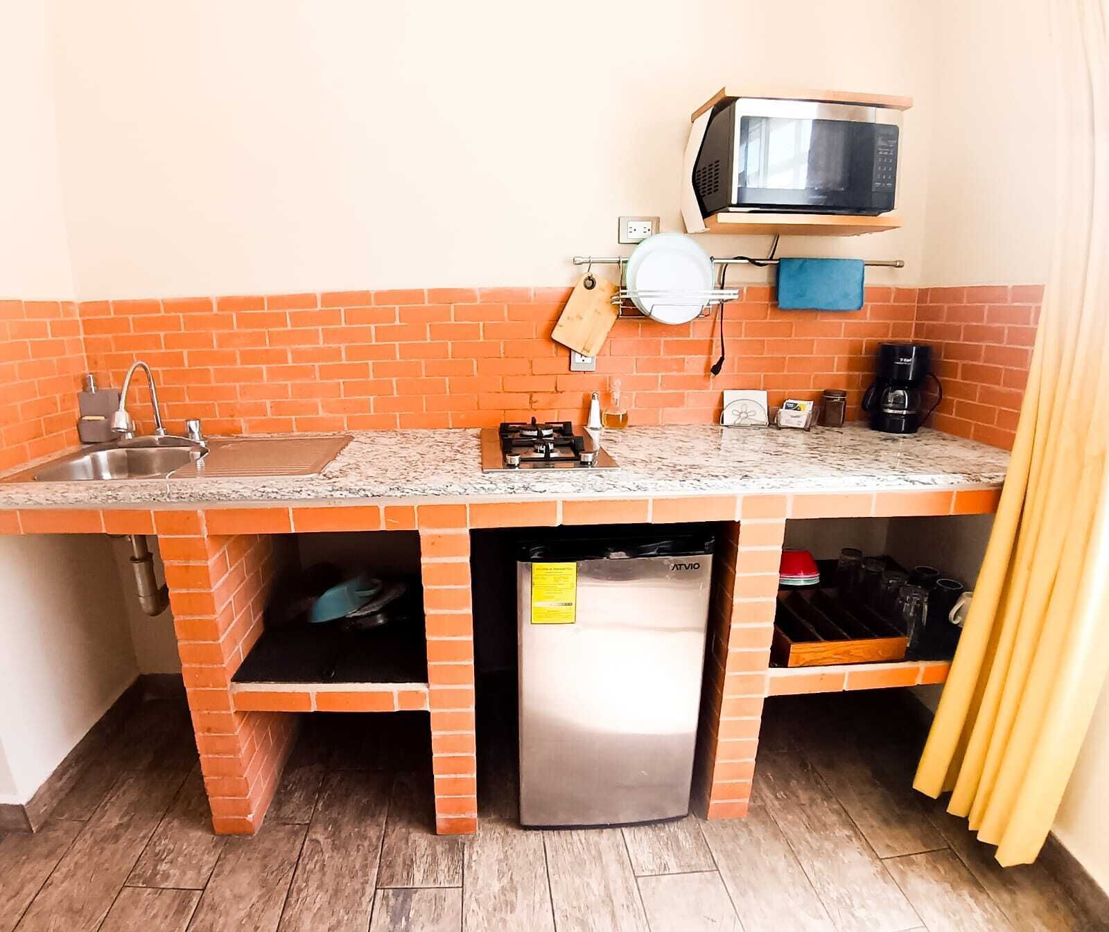 A compact kitchen with a built-in microwave, a sink, and a small refrigerator.