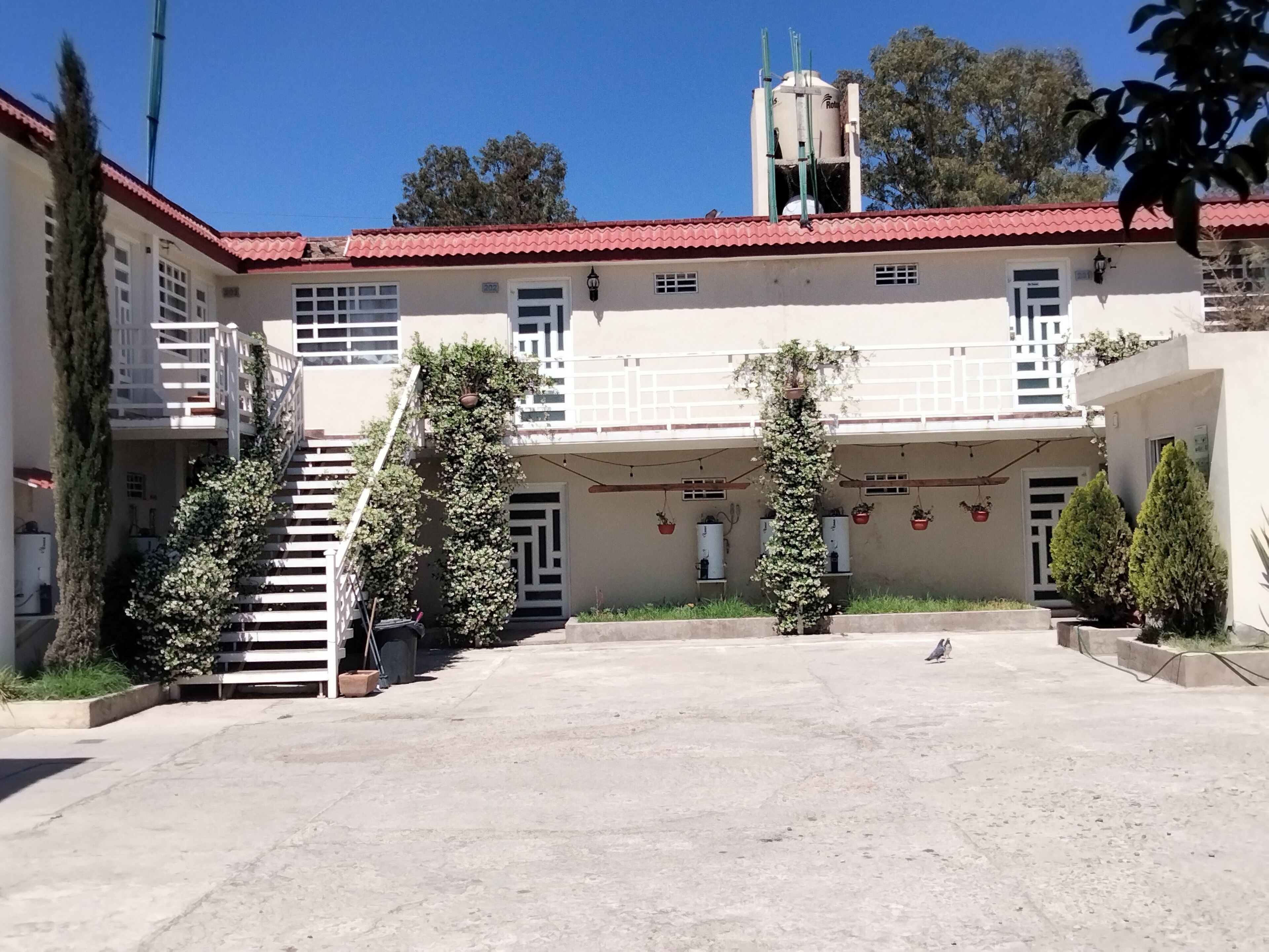A building with a red-tiled roof, a staircase, and potted plants.