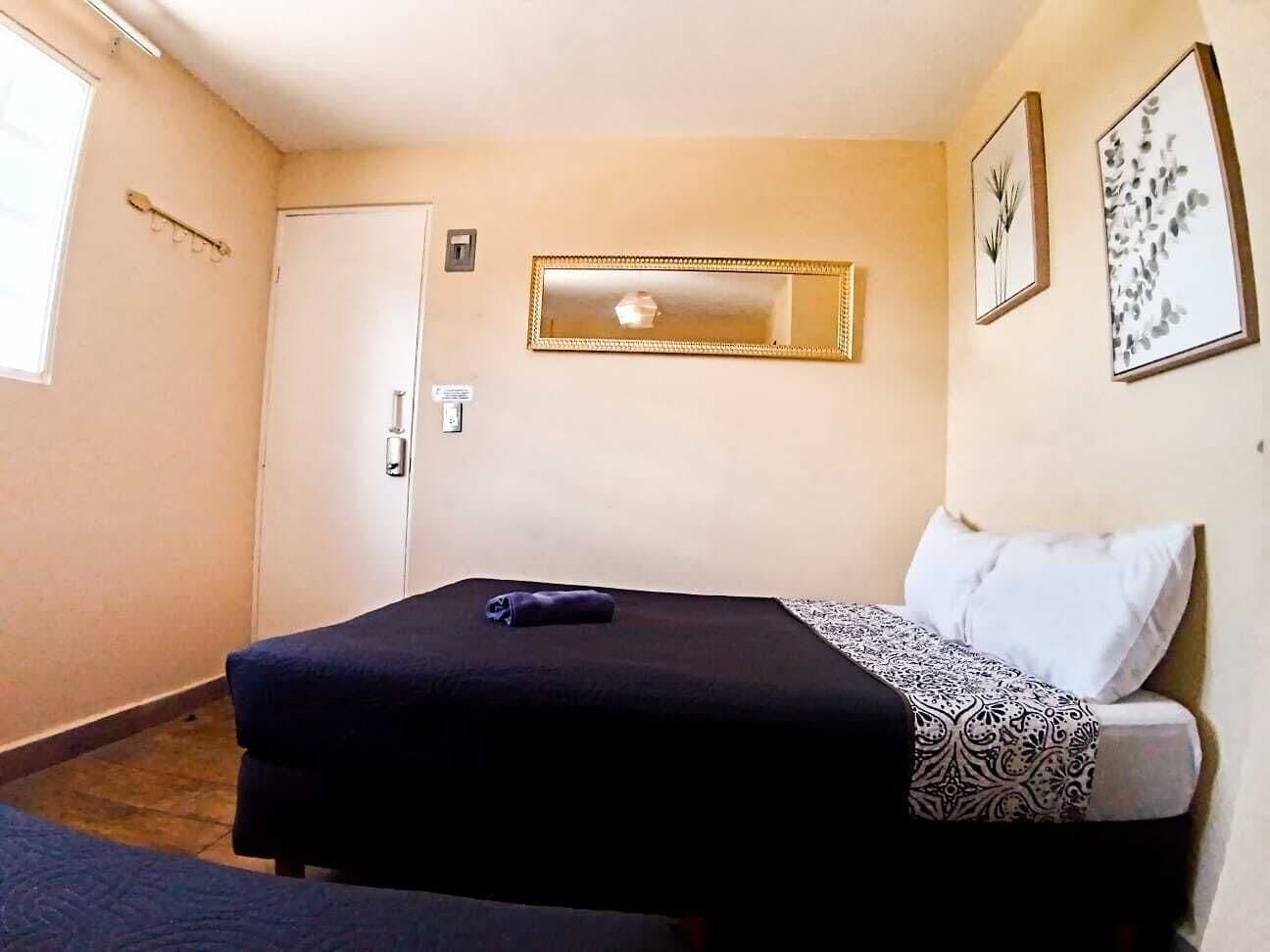 Una habitación pequeña con cama individual, mesita de noche, espejo y puerta.