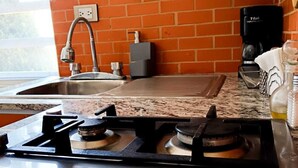 Una cucina con piano in granito, fornello a gas, macchina del caffè e parete rivestita in mattoni.