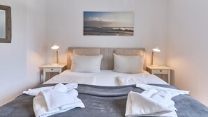 Une chambre d’hôtel avec un lit, deux tables de chevet, un tableau et des serviettes.