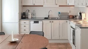 Et moderne køkken med hvide skabe, opvaskemaskine, komfur og vask.