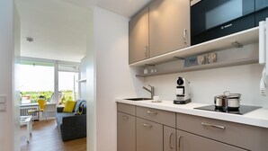 A modern kitchen with a Bosch microwave, a coffee machine, and a pot on the counter.