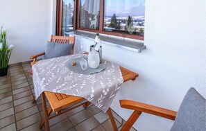 Een klein balkon met een tafel voor twee, een fles champagne en uitzicht op een besneeerd landschap.