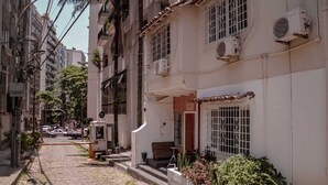 Una estrecha calle adoquinada flanqueada por edificios de varios pisos, algunos con balcones y unidades de aire acondicionado.