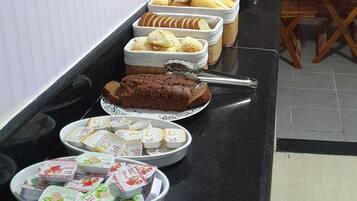 Una mesa de buffet con diversos alimentos, como pan, pastelería y aperitivos empaquetados.
