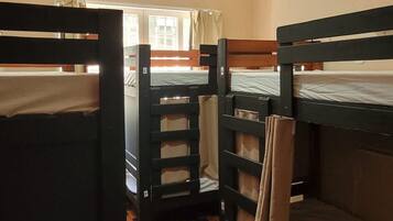Ein Schlafsaalzimmer mit Etagenbetten, einem Deckenventilator und einem Fenster mit Vorhängen.