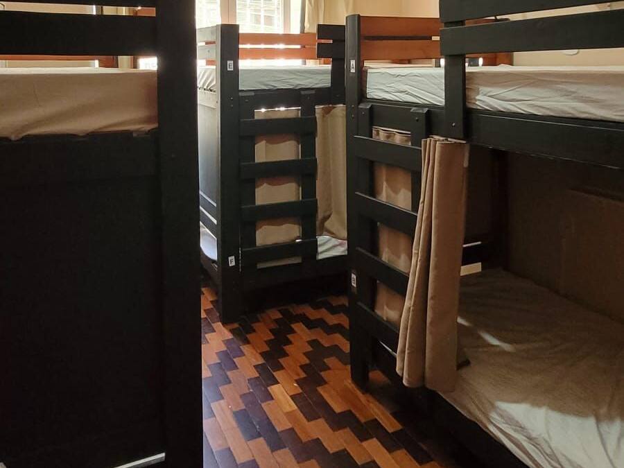 Un dormitorio con literas, ventilador de techo y ventana con cortinas.