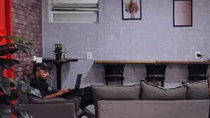 Una sala de estar moderna con un sofá gris, una puerta roja y una pequeña mesa con una planta.