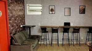 Un espacio habitable compacto con un sofá, una mesa de comedor con sillas y una puerta roja.