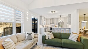 Un salon moderne comprenant un canapé, une table basse et un coin repas avec des chaises.