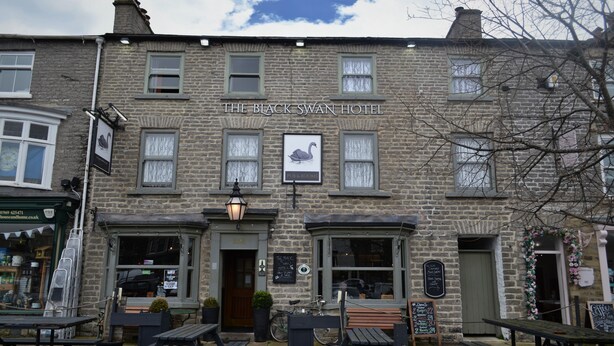 The Black Swan Hotel with stone facade, pub & room sign, outdoor seating, and a bicycle parked outside. - the black swan (Leyburn)