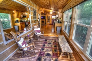 A cabin interior with wooden walls, a kitchen area, and a seating area with chairs and a bench. - BEAUTIFUL PREMIER CABIN!!! 2 bedroom NEWLY RENOVATED CABIN WITH HOT TUB!!! (Helen)