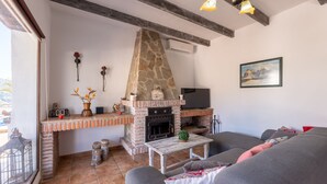 Un saló agradable amb una llar de pedra, una televisió i una zona de seients confortable.