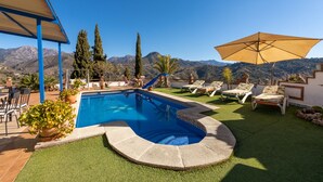 Zona de piscina amb vistes a les muntanyes, gandules i zona de seients coberta.