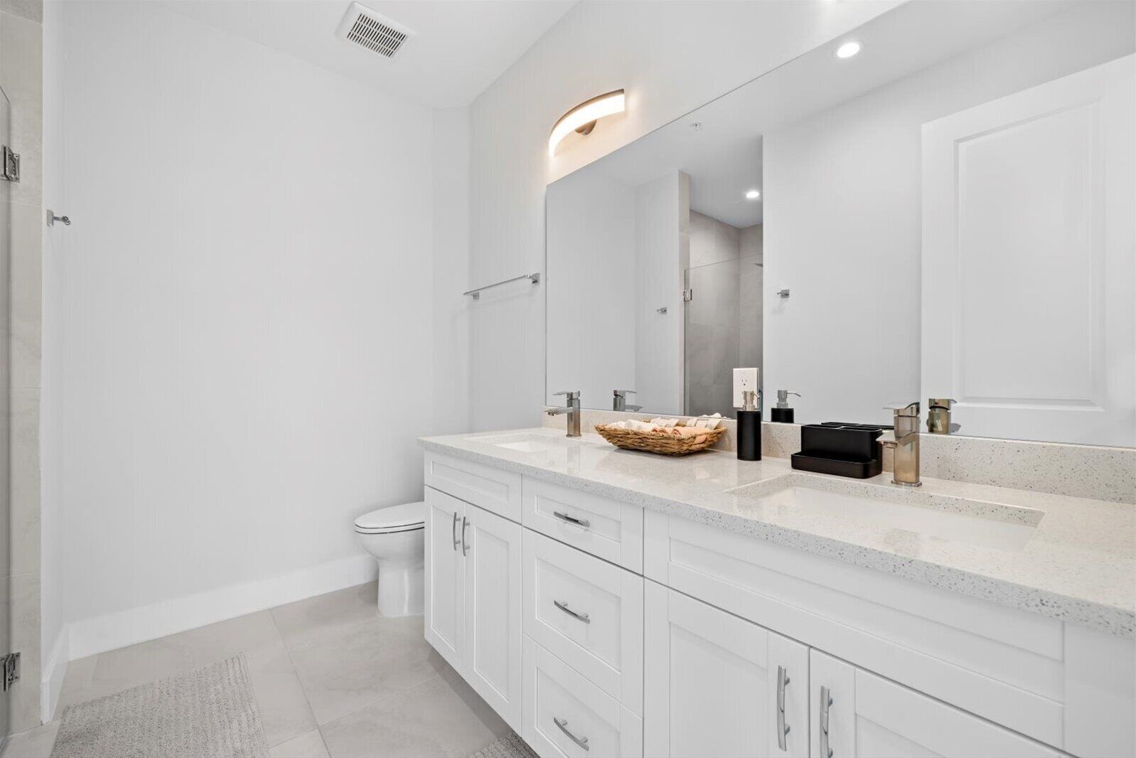A modern bathroom with a large mirror, white cabinetry, and a granite countertop.