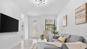 A modern living room with a grey sofa, a coffee table, and a TV mounted on the wall. - NAPLES GEM (Naples)
