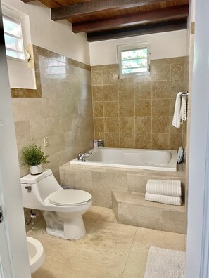 Une salle de bain comprenant des toilettes, un lavabo, une baignoire et une fenêtre.