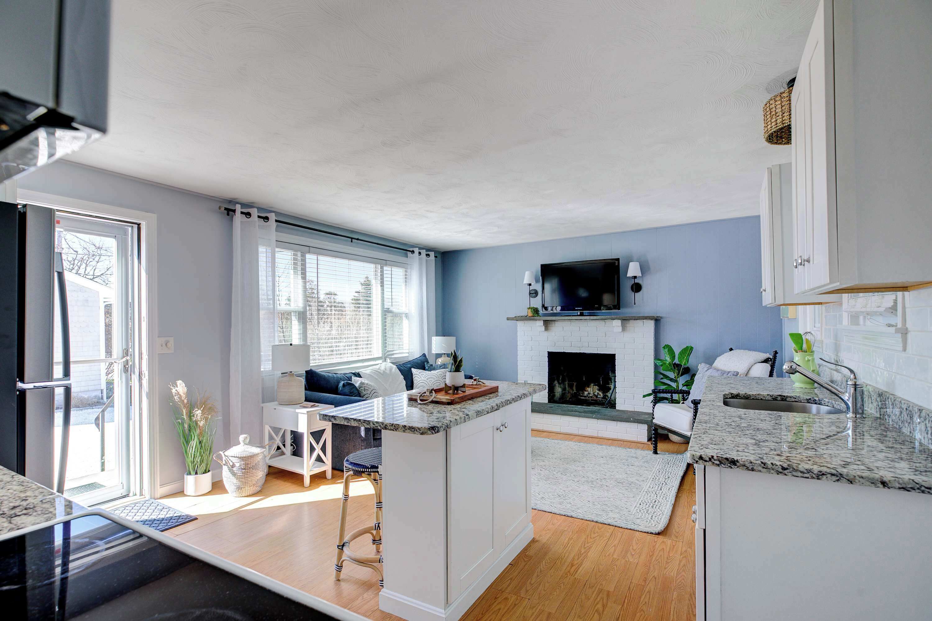 A modern kitchen with a central island, a fireplace, and a dining area with a sofa.