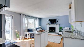 A modern kitchen with a central island, a fireplace, and a dining area with a sofa.