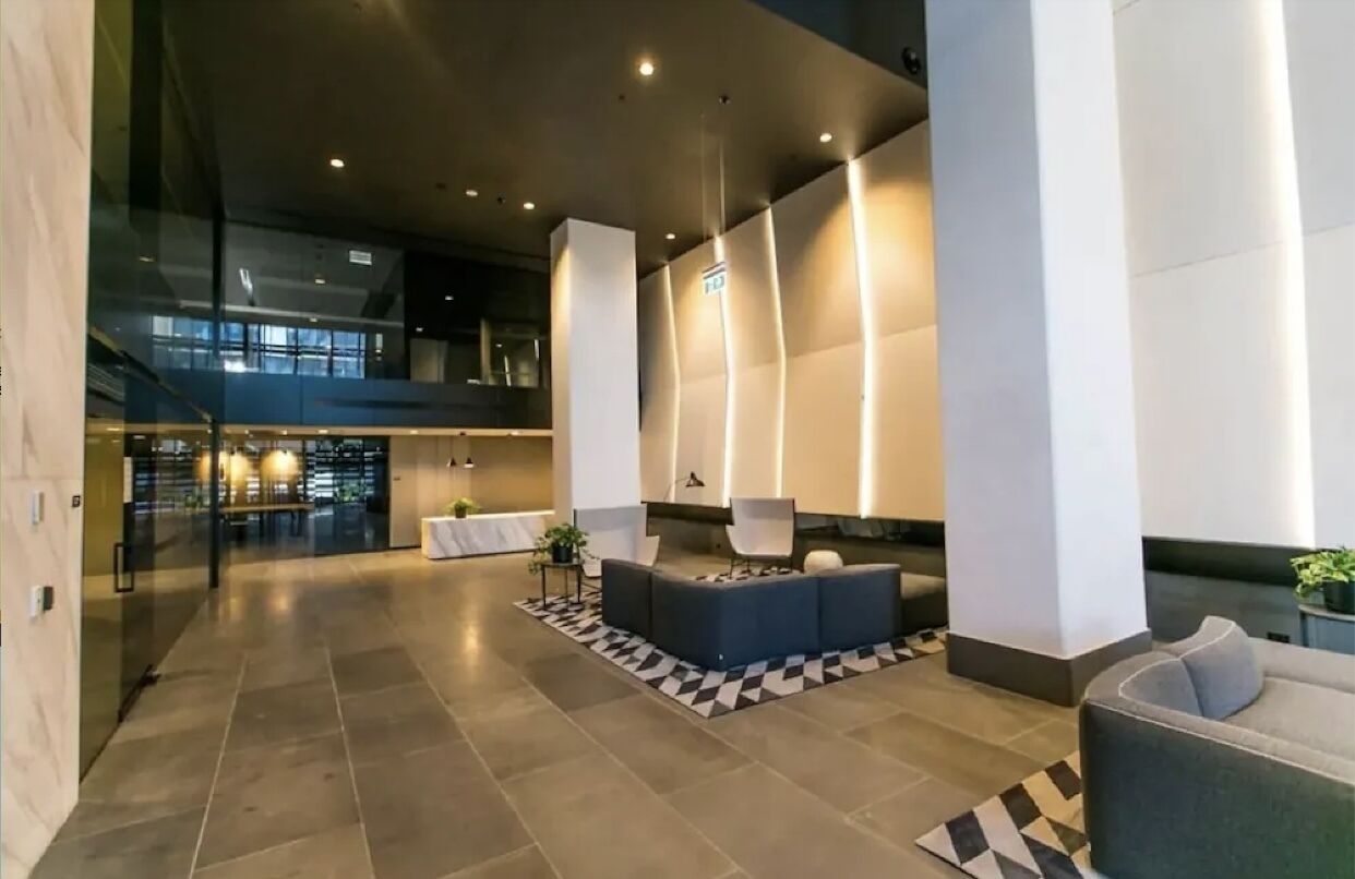 A spacious lobby with a modern design, featuring a seating area with sofas and a patterned rug.